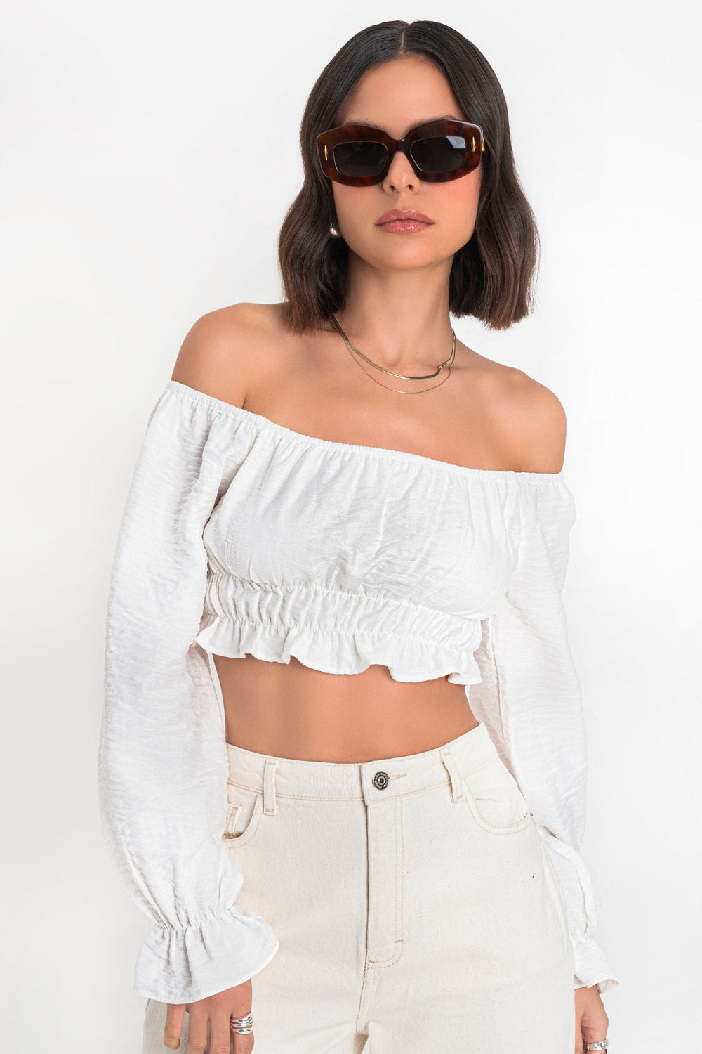 Crop top de manga larga abullonada con rib elástico y olanes en puños, hombros descubiertos, escote recto con rib elástico en borde, bajo con rib elástico y olanes decorativos en borde.