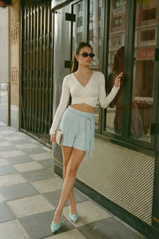 Crop top de escote v cruzado con plisados frontales, manga larga y fit ajustado.