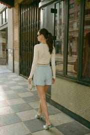 Crop top de escote v cruzado con plisados frontales, manga larga y fit ajustado.