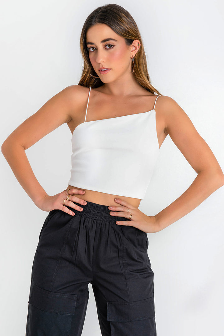 Woman wearing a white crop top and black cargo pants.