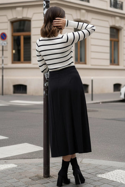 Falda midi de cintura alta con pretina, corte en a, aberturas frontales en bajo, botones decorativos y cierre posterior con cremallera oculta.