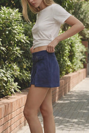 Falda short corto de gamuza, cintura media, fit ajustado y trabilla decorativa lateral con hebilla en contraste. Detalle de abertura frontal en bajo y cierre lateral con cremallera oculta.
