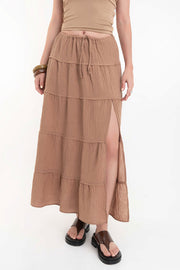 Falda maxi de cintura alta con pretina elástica y jareta frontal ajustable, corte en a, capas de olanes en bajo y abertura lateral.