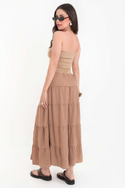 Falda maxi de cintura alta con pretina elástica y jareta frontal ajustable, corte en a, capas de olanes en bajo y abertura lateral.