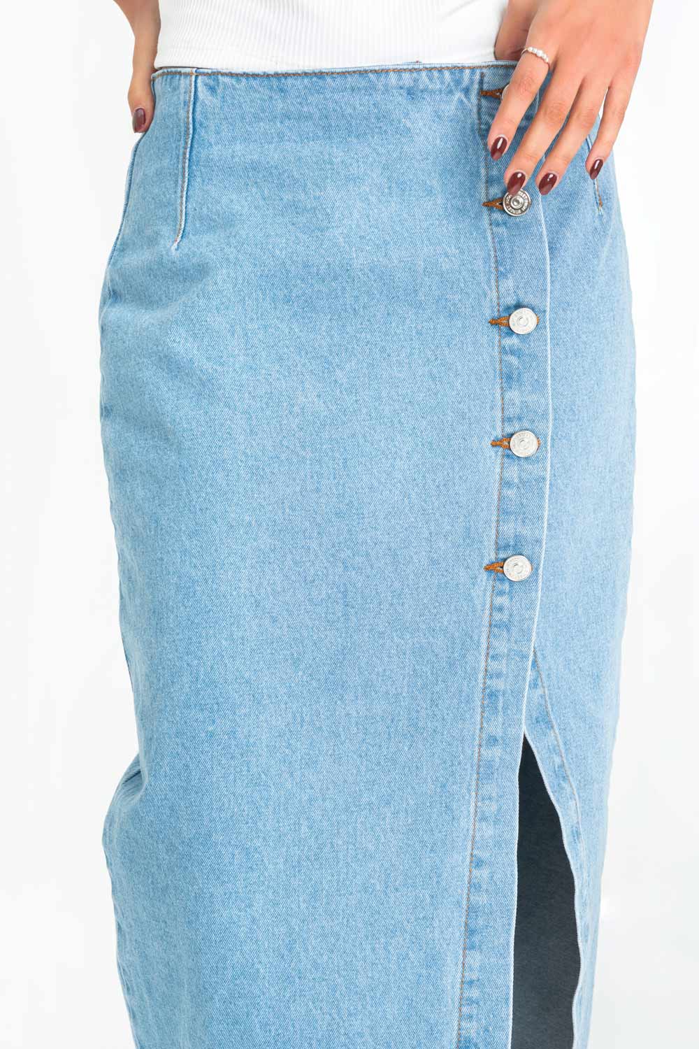 Falda midi de denim, fit ajustado, cintura alta, cruce frontal con hilera lateral de botones en contraste y abertura en bajo. Detalle de bolsillos traseros de parche.