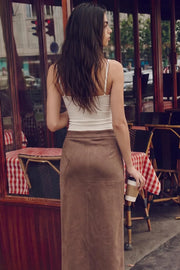 Falda midi de gamuza, fit recto, cintura alta con pretina. Detalle de costuras decorativas y abertura frontal en bajo. Cierre lateral con cremallera oculta.