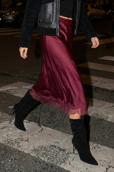 Falda midi satinada de cintura alta con pretina elástica y fit recto. Detalle de encaje en bajo.