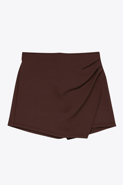 Falda short corto de cintura alta, corte en a, cruce frontal con plisados frontales y cierre lateral con cremallera oculta.