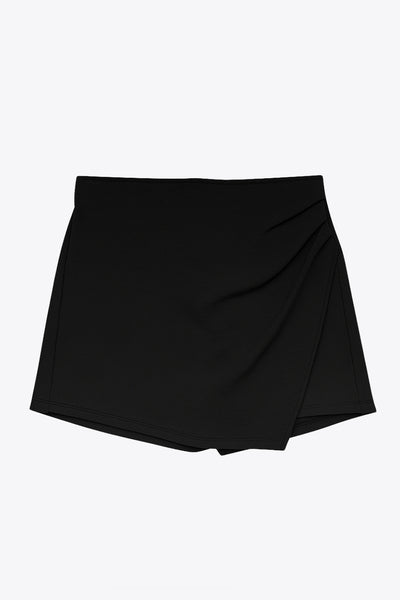 Falda short corto de cintura alta, corte en a, cruce frontal con plisados frontales y cierre lateral con cremallera oculta.