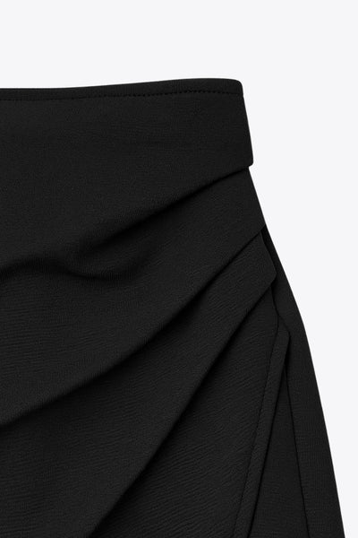 Falda short corto de cintura alta, corte en a, cruce frontal con plisados frontales y cierre lateral con cremallera oculta.