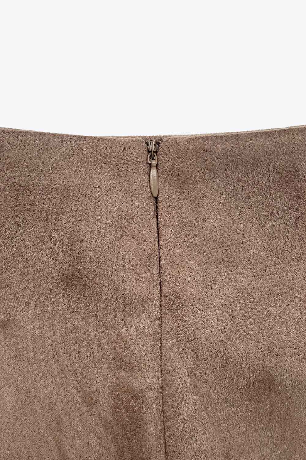 Falda short corto de gamuza, cintura alta, corte en a, costura frontal con abertura en bajo y cierre posterior con cremallera oculta.