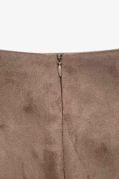 Falda short corto de gamuza, cintura alta, corte en a, costura frontal con abertura en bajo y cierre posterior con cremallera oculta.