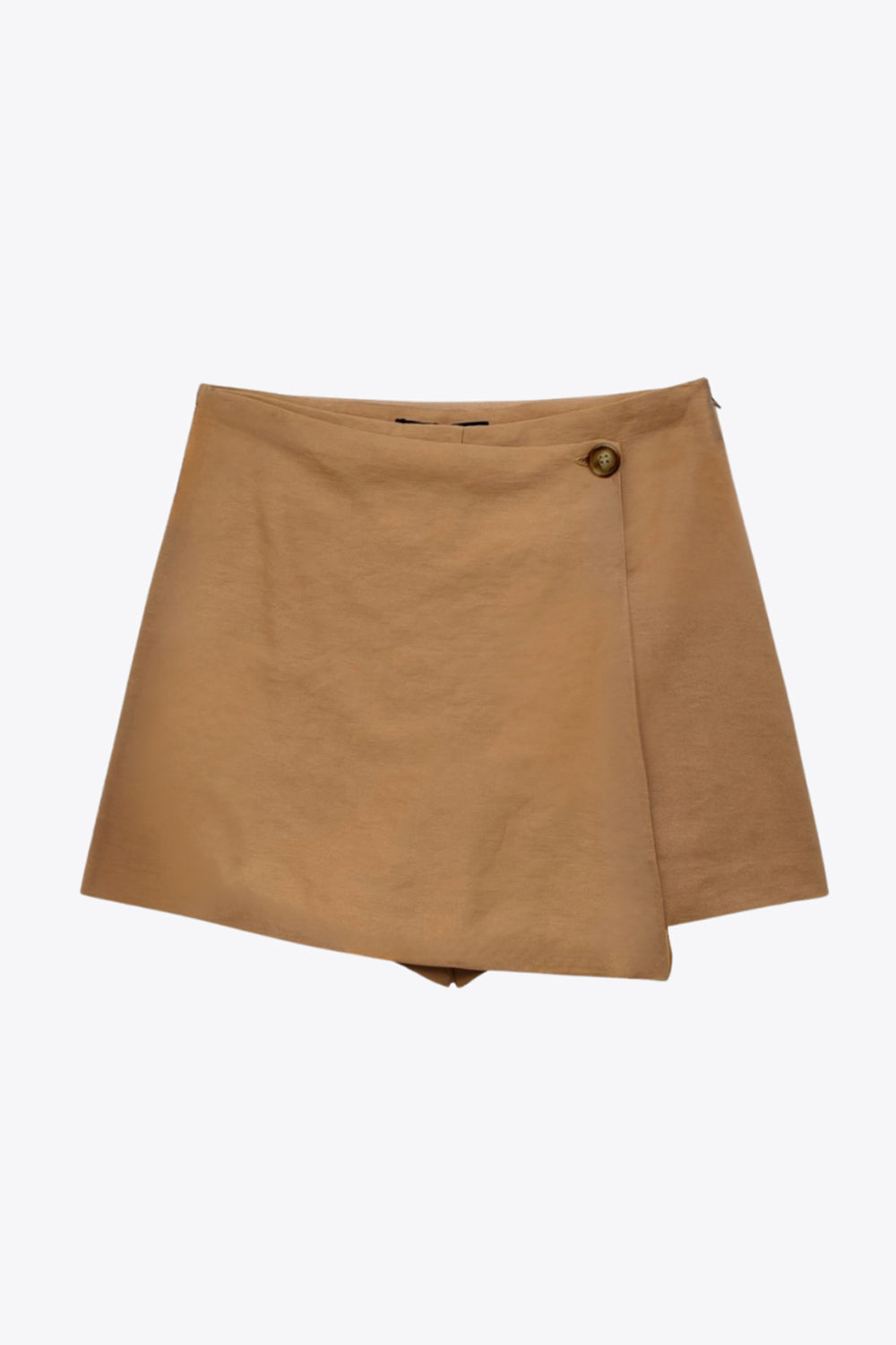 Falda short corto de cintura alta, corte en a, cruce frontal con abertura en bajo y botón en contraste. Cierre lateral con cremallera oculta.