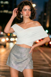 Falda short corto de brillos, corte en a, cintura alta, cruce frontal con abertura y cierre lateral con cremallera oculta.