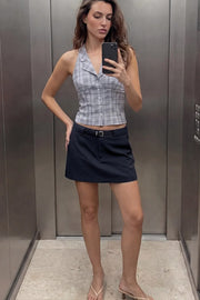 Falda short corto de fit recto, cintura alta con pretina y trabillas, vivos decorativos posteriores, cierre frontal con broche y cremallera ocultos. Detalle de cinturón en contraste con hebilla.