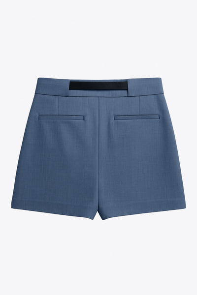 Falda short corto de fit recto, cintura alta con pretina y trabillas, vivos decorativos posteriores, cierre frontal con broche y cremallera ocultos. Detalle de cinturón en contraste con hebilla.