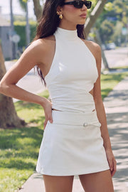 Falda short corto de cintura media, fit ajustado y cinturón decorativo con hebilla en contraste. Cierre lateral con cremallera oculta.