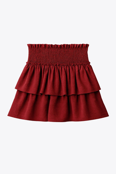 Falda short de corte en a, cintura alta elástica con pretina fruncida y capas de olanes en bajo.