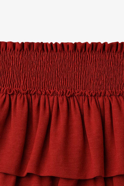 Falda short de corte en a, cintura alta elástica con pretina fruncida y capas de olanes en bajo.