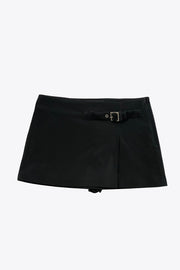 Falda short corto de fit recto, cintura alta, trabilla decorativa con hebilla en contraste, abertura frontal en bajo y cierre lateral con cremallera oculta.