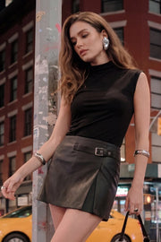 Falda short corto de efecto piel, fit recto, cintura alta, trabilla decorativa con hebilla en contraste, abertura frontal en bajo y cierre lateral con cremallera oculta.