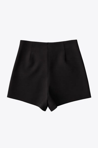 Falda short corto de fit ajustado, cintura alta, cruce frontal con nudo y plisados decorativos frontales. Cierre posterior con cremallera oculta.