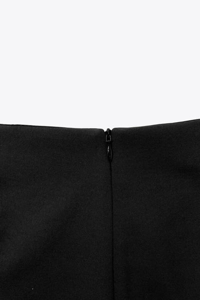 Falda short corto de fit ajustado, cintura alta, cruce frontal con nudo y plisados decorativos frontales. Cierre posterior con cremallera oculta.