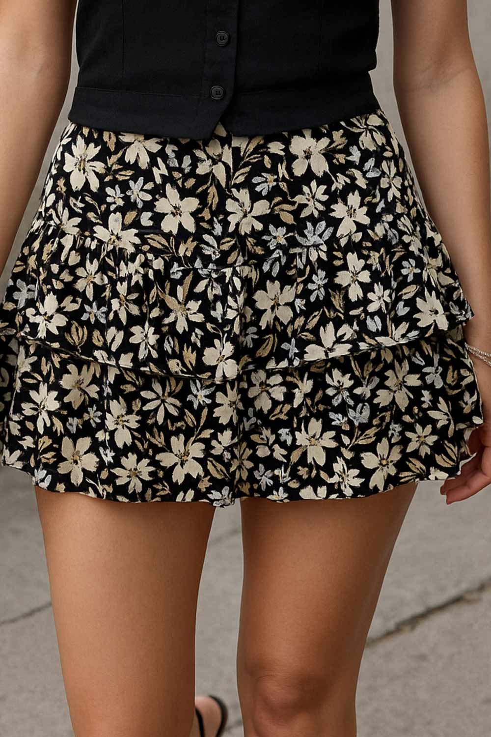 Falda short corto de estampado floral, cintura baja con pretina y jareta frontal ajustable, corte en a y capas de olanes en bajo.