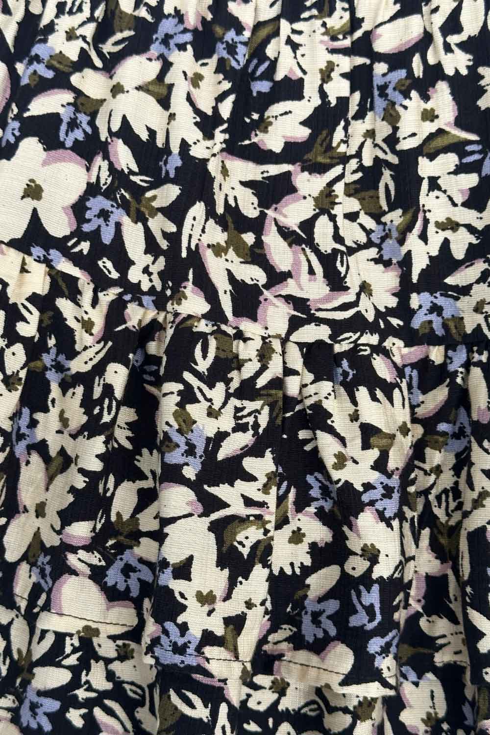 Falda short corto de estampado floral, cintura baja con pretina y jareta frontal ajustable, corte en a y capas de olanes en bajo.