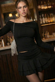 Falda short corto de cintura alta con pretina con plisados decorativos laterales, corte en a y bajo con capas de olanes. Cierre lateral con cremallera oculta.