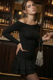 Falda short corto de cintura alta con pretina con plisados decorativos laterales, corte en a y bajo con capas de olanes. Cierre lateral con cremallera oculta.