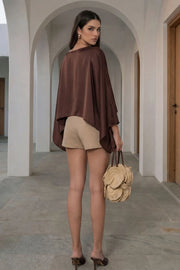 Falda short corto de cintura alta, corte en a, cruce frontal asimétrico con plisados laterales y cierre lateral con cremallera oculta.