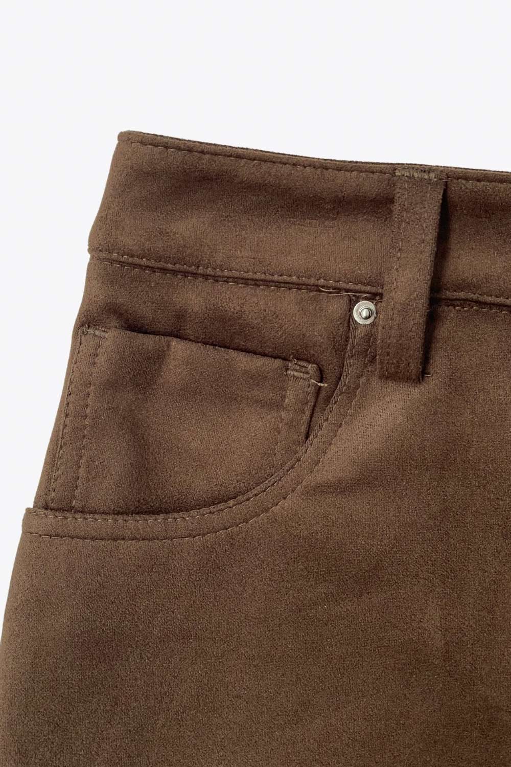 Falda short corto de gamuza, fit ajustado, cintura alta con pretina y trabillas, bolsillos delanteros, cierre frontal con botón y cremallera oculta.