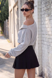 Falda short corto tableado, de cintura alta con pretina y trabillas, corte en a, cierre frontal con broche y cremallera ocultos.
