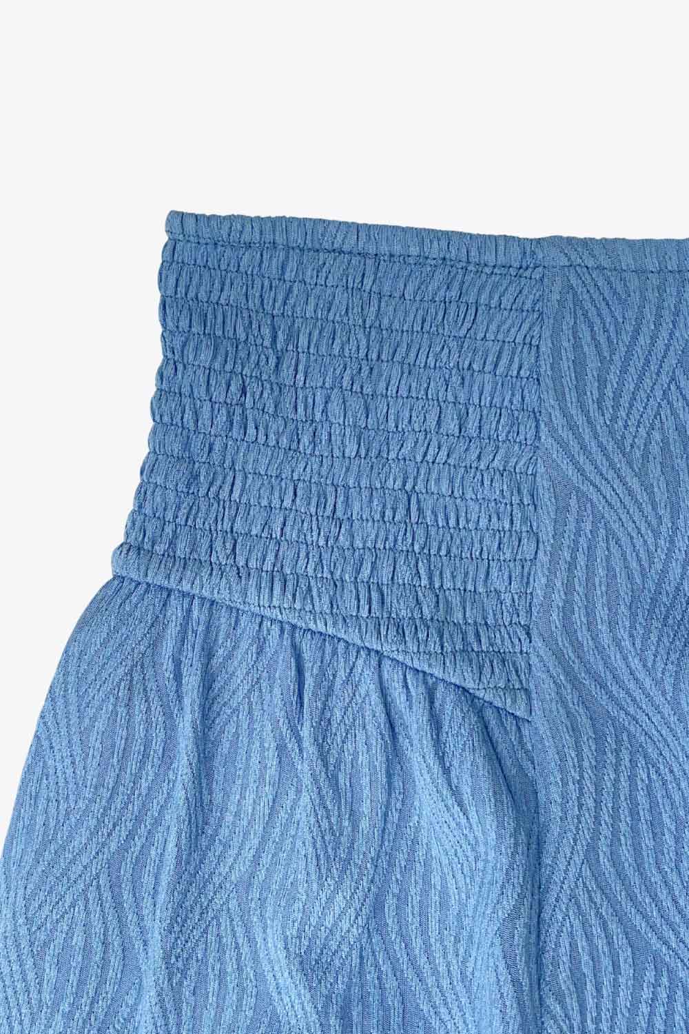 Falda short corto de cintura alta elástica, corte en a, fruncidos con plisados en costados y detalle de textura en tejido.