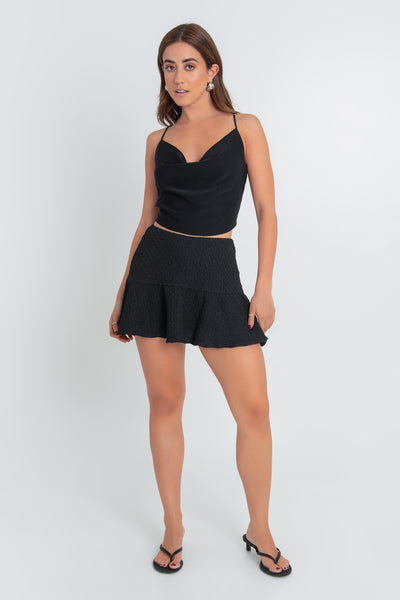 Falda short corto de cintura alta elástica con pretina ancha y olanes en bajo. Detalle de textura en tejido.