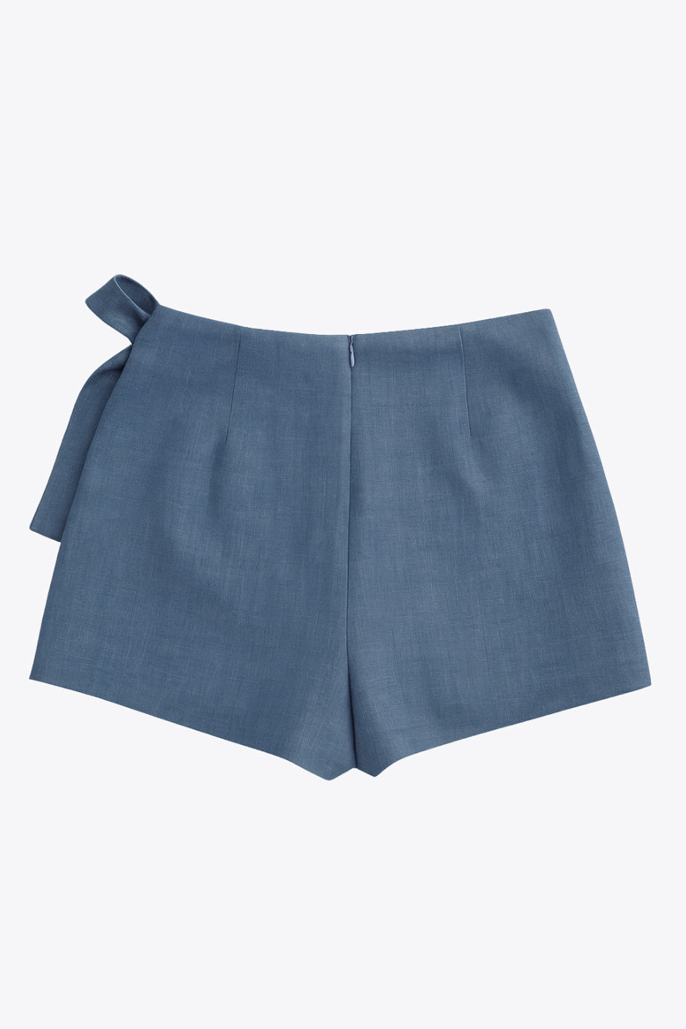 Falda short corto de cintura alta, corte en a, sobrefalda con cruce frontal, lazo lateral amarrable y cierre posterior con cremallera oculta.