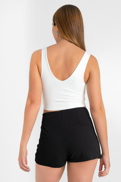 Falda short corto de fit ajustado, cintura alta, cruce frontal con bajo asimétrico y cierre posterior con cremallera oculta.