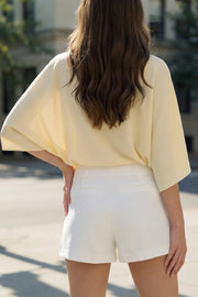 Falda short corto de fit ajustado, cintura alta, cruce frontal con bajo asimétrico, vivos decorativos posterior y cierre lateral con cremallera oculta.