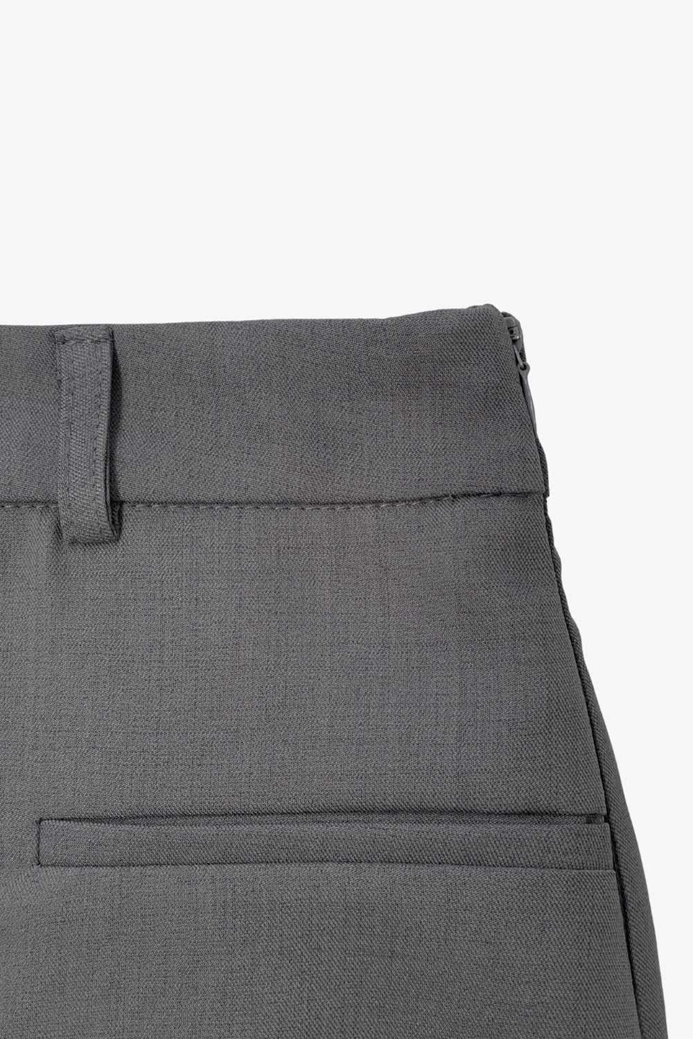 Falda short corto de cintura alta con pretina y trabillas, corte en a, cruce frontal en diagonal y vivos decorativos frontales. Cierre lateral con cremallera oculta.