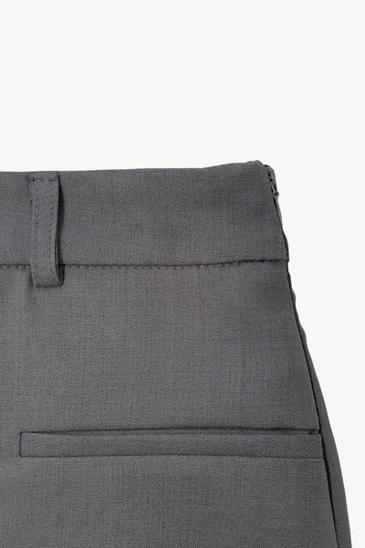 Falda short corto de cintura alta con pretina y trabillas, corte en a, cruce frontal en diagonal y vivos decorativos frontales. Cierre lateral con cremallera oculta.