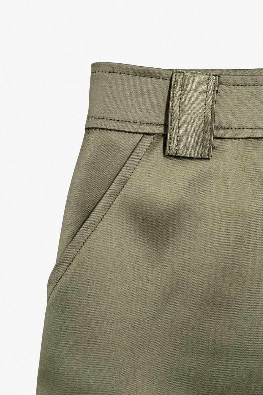 Falda short corto satinado de cintura alta con pretina y trabillas, corte en a, bolsillos delanteros y laterales cargo con cartera. Cierre frontal con broche y cremallera ocultos.