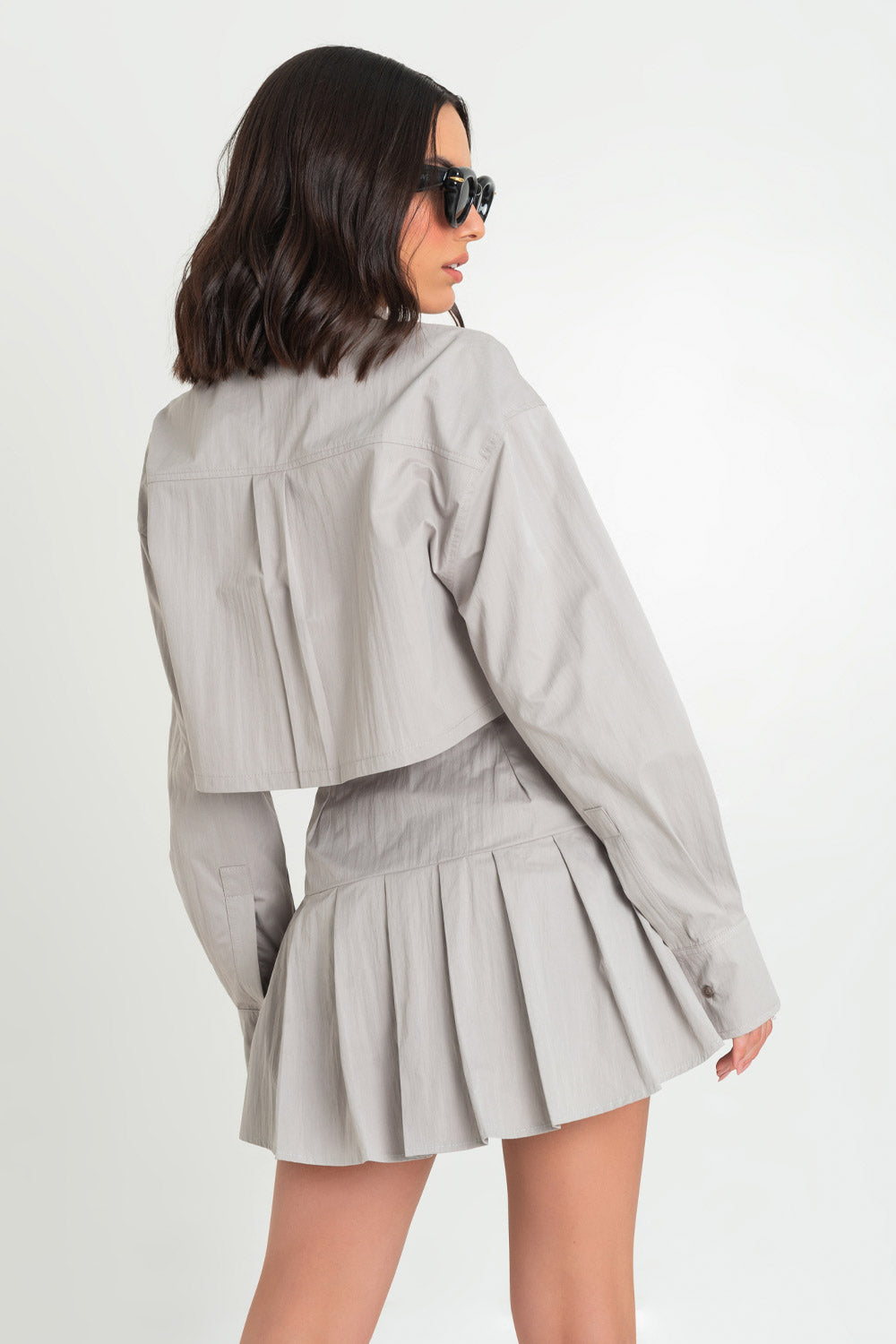 Falda short corto de cintura alta con pretina ancha, tableado en bajo y trabillas decorativas laterales con hebillas en contraste. Cierre lateral con cremallera oculta.