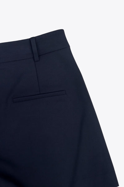 Falda short corto tableado de cintura alta con pretina y trabillas, corte en a, pinzas frontales y vivo decorativo posterior. Cierre frontal con broche y cremallera ocultos.