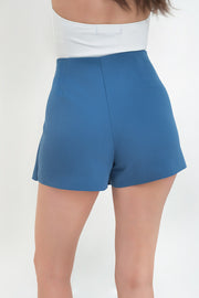 Falda short corto de cintura alta, corte en a, cruce frontal en diagonal y cierre lateral con cremallera oculta.