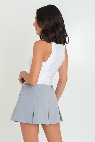 Falda short corto tableado, de cintura alta, pretina con trabillas y detalle de boxer en contraste. Cierre lateral con cremallera oculta.