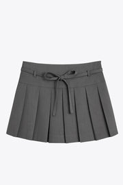 Falda short corto tableado, de corte en a, cintura alta con pretina, trabillas y lazo amarrable del tejido. Detalle de tableado en bajo y cierre lateral con cremallera oculta.