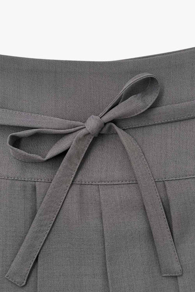 Falda short corto tableado, de corte en a, cintura alta con pretina, trabillas y lazo amarrable del tejido. Detalle de tableado en bajo y cierre lateral con cremallera oculta.