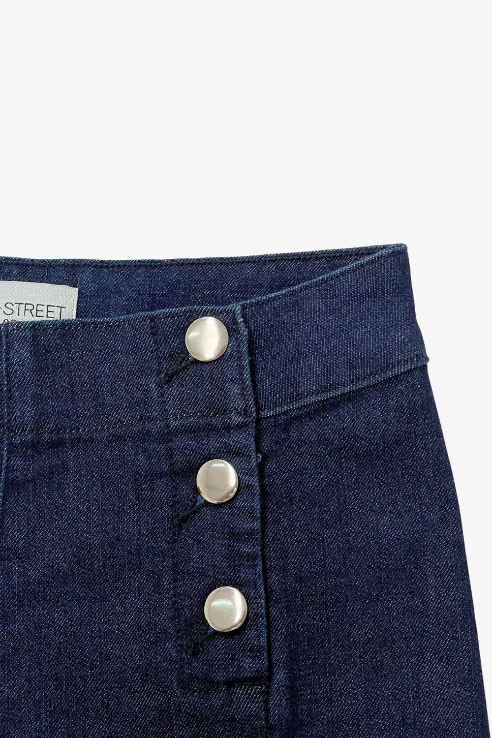Pantalón de denim, fit wide leg, tiro alto, cintura alta con pretina y trabillas, bolsillos traseros de parche y cierre frontal con botones tipo marinero en contraste.