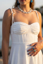 Maxi vestido de corte en a, tirantes delgados con nudo amarrable, escote corazón con cortes y detalles plisados. Cierre posterior con cremallera visible en contraste y olanes en borde de bajo.